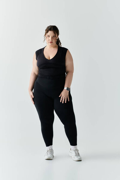 A beautiful plus size woman poses gracefully in fitted black attire, showcasing her elegance.