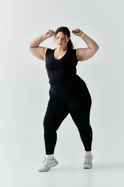 Красивая плюс размер женщина демонстрирует свою грацию и силу в стильном черном платье тренировки.