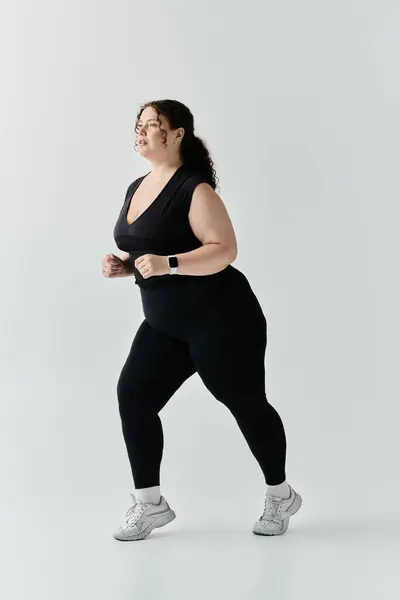 stock image A graceful plus size woman enjoys a confident stroll in stylish activewear under natural lighting.