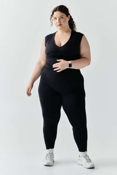 Уверенная в себе женщина с большим размером демонстрирует свою красоту с изяществом, одетая в шикарный черный ансамбль.