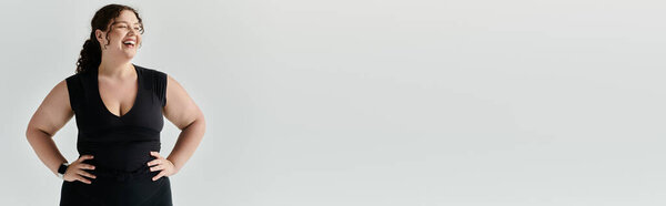 An elegant plus size woman radiates confidence while posing and smiling against a simple backdrop.