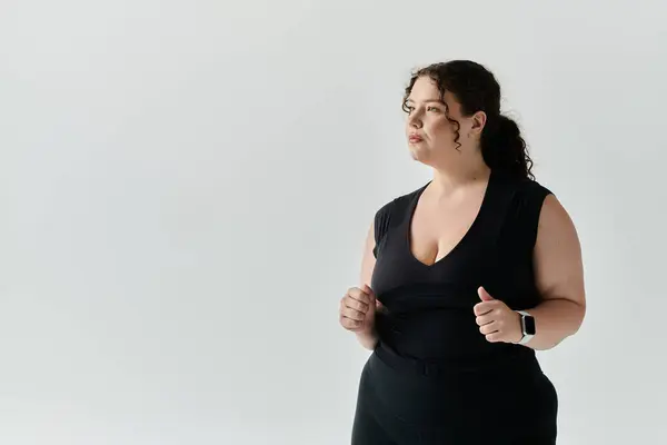 stock image A graceful plus size woman stands confidently, showcasing her elegance in a simple studio.