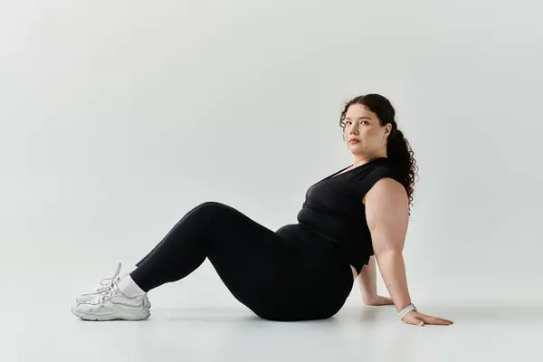 stock image A stunning plus size woman radiates self confidence while seated elegantly on a clean surface.