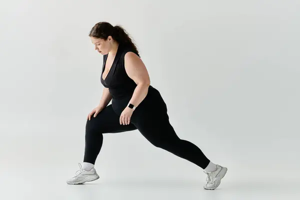 stock image A poised, beautiful woman is stretching in a modern, airy space with minimal decor.