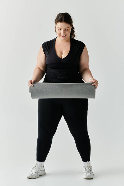 Изящный плюс размер женщина держит циновку yoga, готово принять успокаивающую практику.