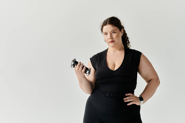 A beautiful plus size woman stands poised, holding weights, radiating self assuredness and style.