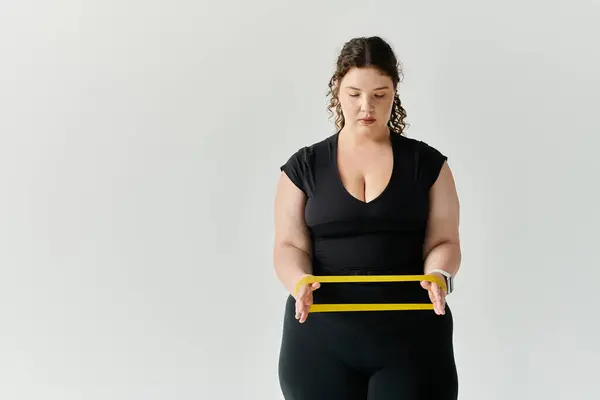 stock image A graceful plus size woman skillfully uses resistance bands to enhance her workout routine.