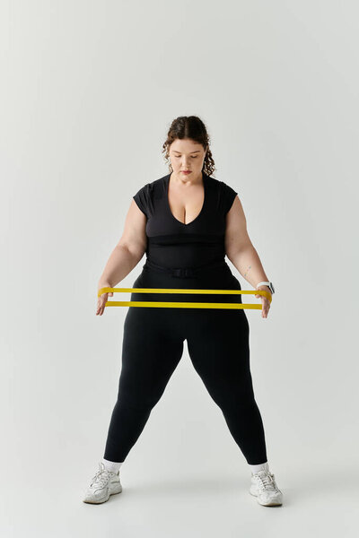 Элегантная женщина плюс размер укрепляет свое тело с помощью бандажей сопротивления в гладкой студии.