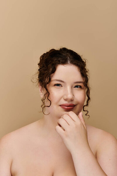 A confident and elegant plus size woman smiles softly against a warm backdrop, radiating beauty.