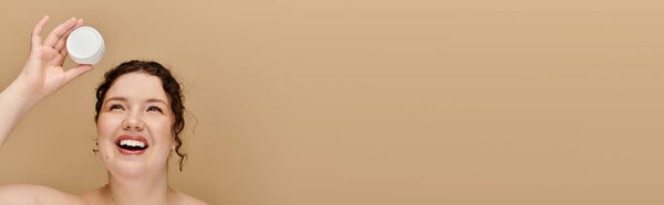 A joyful plus size woman showcases her radiant smile while holding a skincare jar high.