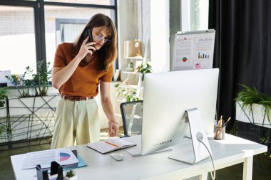 İkili olmayan genç bir insan telefonda konuşuyor, modern ofis düzenine odaklanmış..