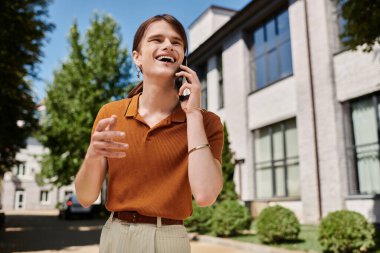 Neşeli, ikili olmayan biri ofis dışında güneşli bir telefon görüşmesi yapmaktan hoşlanır..