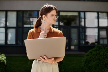 Derin düşüncelere dalmış, ikili olmayan biri ofis ortamında dizüstü bilgisayarındaki fikirleri keşfeder..