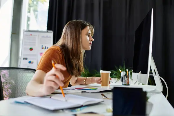 stock image An engaged young non binary individual concentrates on their task at a stylish office desk.