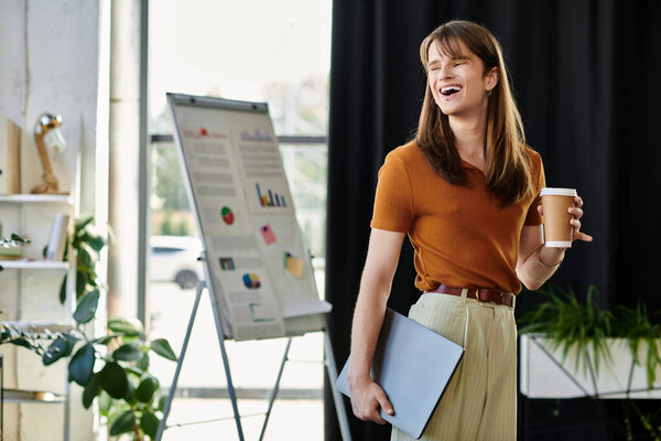 В оживленной офисной среде молодой небинарный человек делится идеями, улыбаясь.