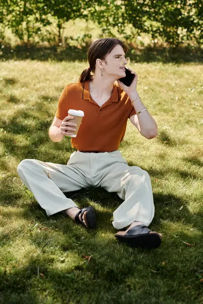 stock image A non binary person enjoys coffee while chatting in a relaxed outdoor setting.