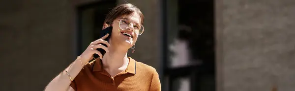 stock image A non binary individual engages in a lively conversation on their phone in a bright office.