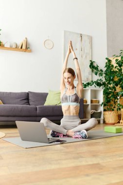 İştahı açık genç bir kadın oturma odasında yoga yapıyor ve sağlık yolculuğuna odaklanıyor..