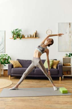İştahsızlığı olan kararlı genç bir kadın evde yoga yapıyor. Forma girme ve kendini geliştirme konusundaki kararlılığını vurguluyor..