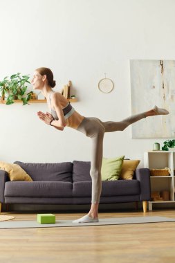 İştahsızlığı olan genç bir kadın evde yoga pratiği yapıyor. Her gün güç ve denge için çabalıyor..