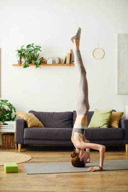 Genç bir kadın evde yoga pozu veriyor, kişisel zorluklar arasında spor yapmaya olan bağlılığını vurguluyor..