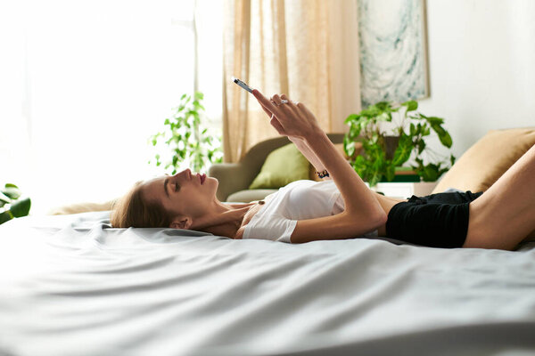 A young woman lies on her bed, absorbed in her phone, amidst a serene, plant-filled living space.