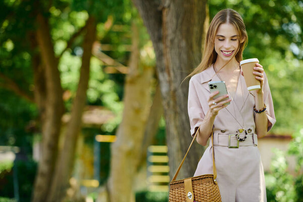 A cheerful young woman with anorexia embraces her outdoor surroundings, sipping coffee and connecting with friends on her phone, radiating happiness.