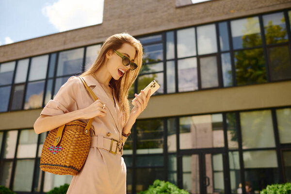 A vibrant young woman smiles as she enjoys a sunny day outdoors, connecting with others through her phone.