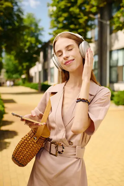 stock image A young woman with headphones savors a joyful moment outdoors, soaking up the sun and engaging with her surroundings.