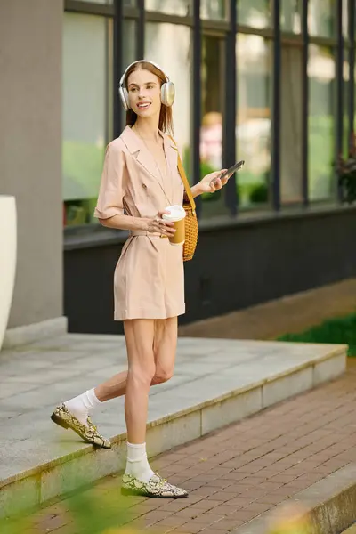 stock image A joyful young woman with anorexia experiencing moments of happiness outdoors, savoring her drink while listening to music, embracing life.