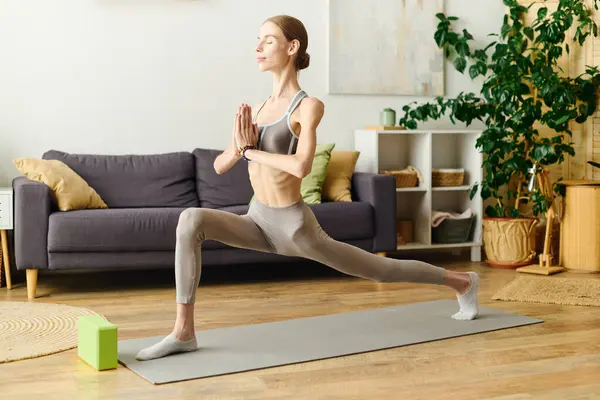 stock image A young woman with anorexia engages in a yoga pose at home, surrounded by greenery and a peaceful atmosphere, focusing on wellness.