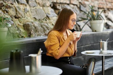 Sıcak bir kafede, genç bir kadın kahvesini yudumluyor, günlük yaşamını kucaklarken esneklik ve neşe katıyor..