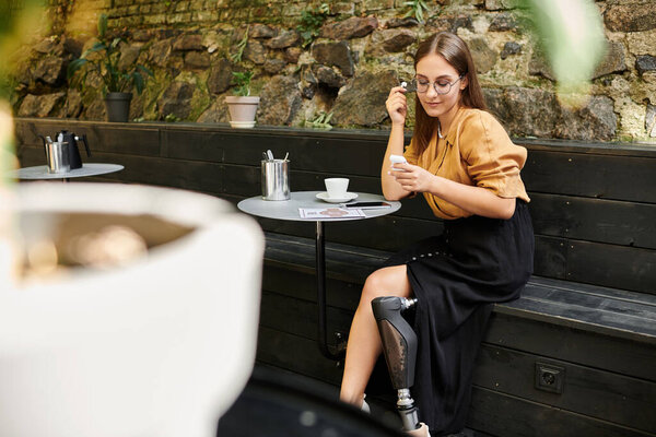 В уютном кафе молодая женщина с протезной ногой наслаждается кофе, наслаждаясь своим ярким образом жизни, расслабляясь.