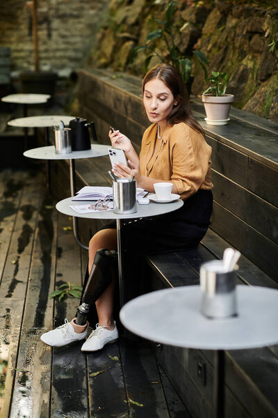 В уютном кафе молодая женщина расслабляется за чашкой кофе, демонстрируя свое уникальное путешествие с протезной ногой.