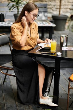 Genç bir kadın bir kafe masasında rahatça oturup yemeğinin tadını çıkarırken, günlük rutinini hiç zorlanmadan yönetiyor..