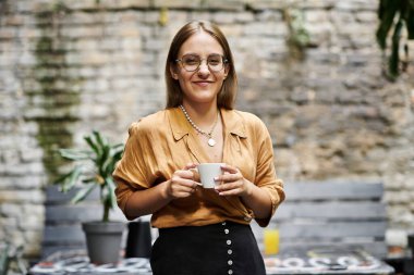 Genç bir kadın bir fincan kahveyle rahatlamış bir kafe atmosferinde eğleniyor..