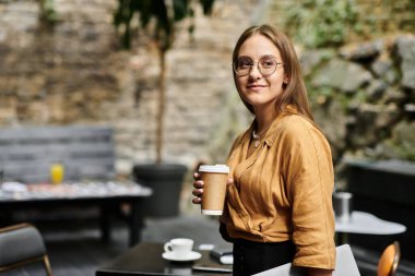 Genç bir kadın rahat bir kafede kahvesinin tadını çıkarıyor, günlük hayatı kucaklıyor..