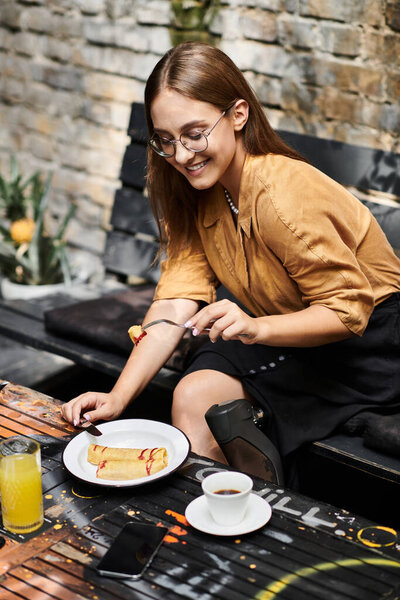 Молодая женщина с искусственной конечностью улыбается, наслаждаясь бранчем в кафе, обнимая свой повседневный образ жизни с радостью.