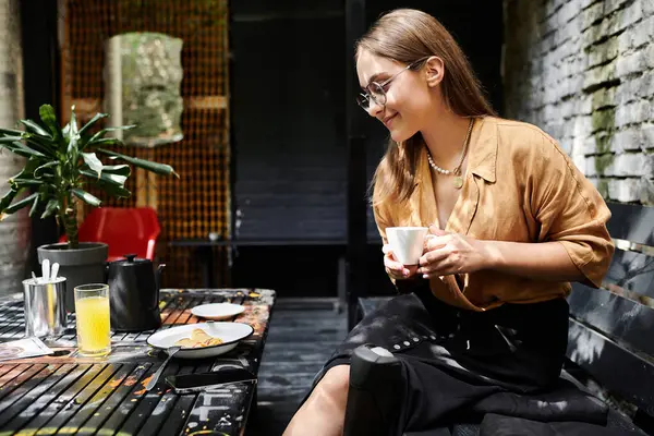 Yapay bacaklı genç bir kadın rahat bir kafede kahvenin tadını çıkarırken gülümsüyor ve hayat dolu yaşam tarzını sergiliyor..