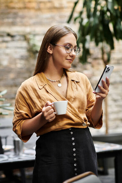 A young woman sips coffee while checking her phone, enjoying a relaxed moment in a cafe setting.