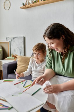 A plus size woman and her daughter enjoy a fun afternoon coloring together at home. clipart