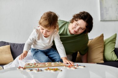 A loving plus size woman watches her daughter play with colorful puzzle pieces on a table. clipart