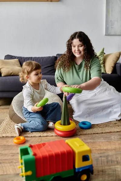 Stock image A plus size woman and her daughter happily engage with colorful toys on the living room floor.