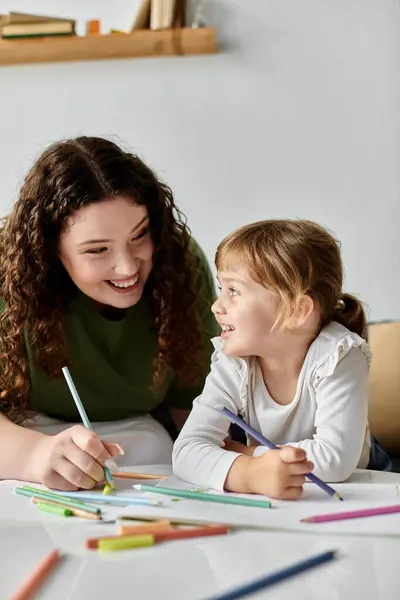 Stock image A loving moment captured as a mother and daughter enjoy drawing together with vibrant colors.