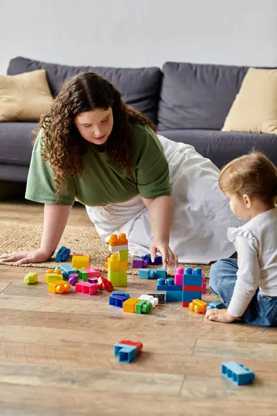 stock image A nurturing mother engages creatively with her daughter, surrounded by colorful building blocks.