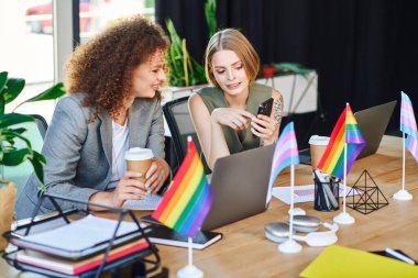 Two coworkers share ideas over coffee while celebrating diversity in the workplace. clipart