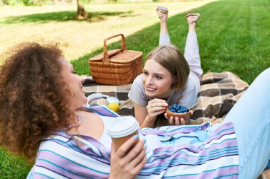 İki arkadaş keyifli anları paylaşır, battaniyenin üzerinde dinlenir, lezzetli atıştırmalıkların tadını çıkarırlar..