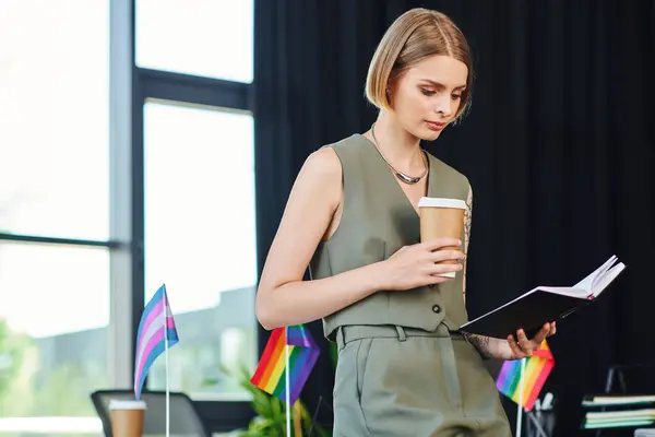 stock image A thoughtful woman reviews notes in a lively office adorned with pride flags.