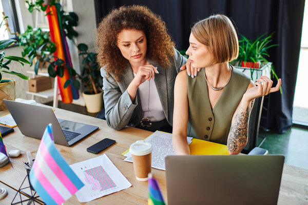 Two coworkers engage in a lively discussion, showcasing their support for the LGBTQ community.