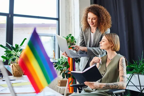 stock image Two team members discuss creatively amid vibrant decor that promotes inclusivity.